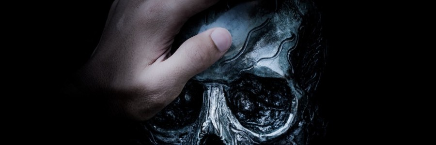 A close up of a man's hand placed on top of a skull