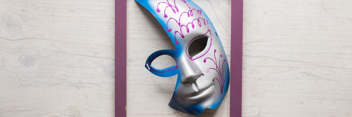 A cut out silver face mask missing half a forehead and cheek framed in a purple colored frame